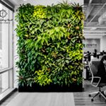 Modern office interior featuring a lush floor-to-ceiling vertical garden design with tropical plants.